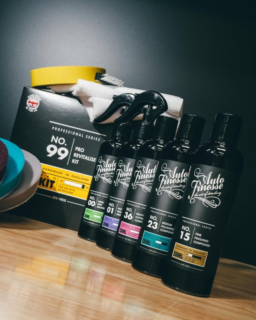 A collection of car cleaning and detailing products, including bottles labeled with numbers and descriptions, alongside a polishing cloth and tape, displayed against a dark background.